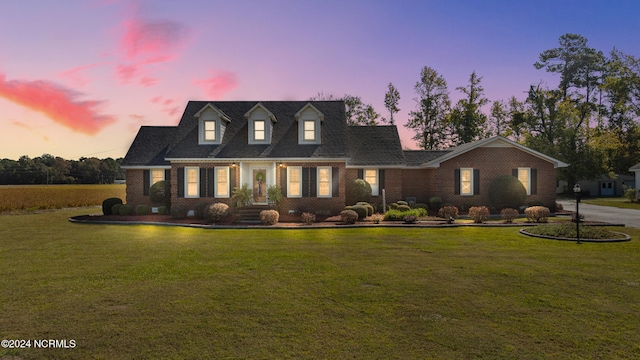 cape cod home featuring a yard