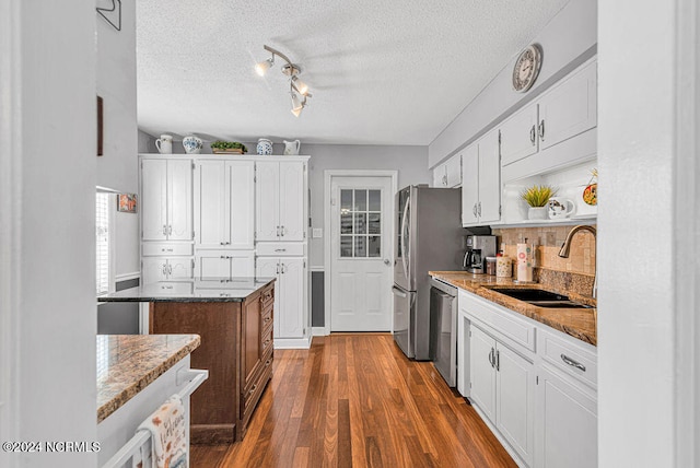 kitchen featuring stainless steel dishwasher, sink, white cabinetry, and dark wood-type flooring