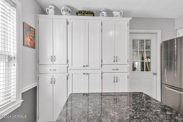 interior space with stainless steel fridge and a textured ceiling