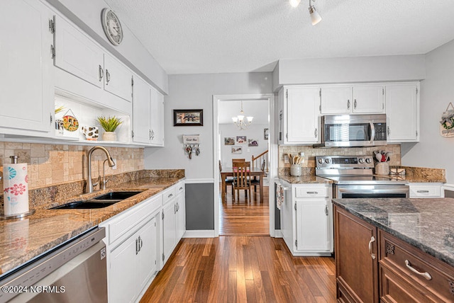 kitchen with dark hardwood / wood-style floors, stainless steel appliances, dark stone countertops, sink, and white cabinetry