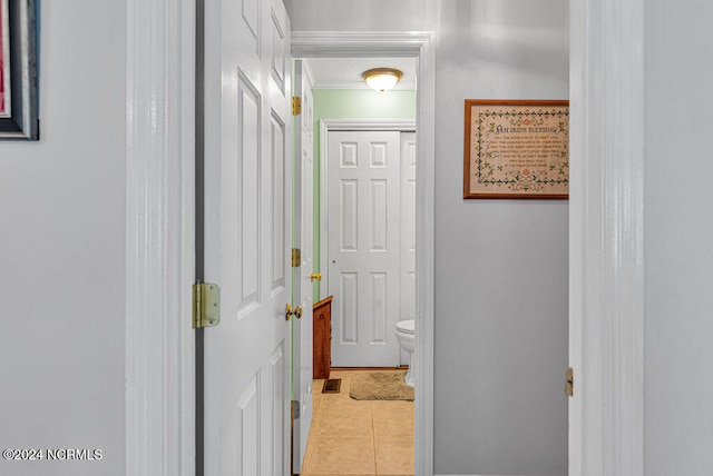 hall with ornamental molding and light tile patterned floors