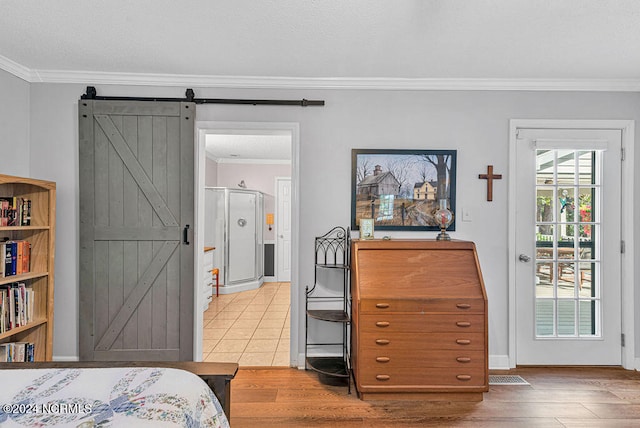 bedroom featuring hardwood / wood-style flooring, ornamental molding, and a barn door