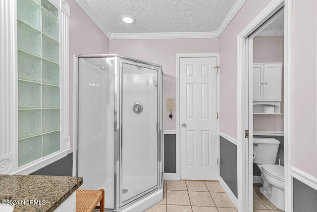 bathroom featuring toilet, tile patterned flooring, a shower with shower door, crown molding, and a textured ceiling