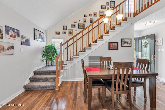 dining area featuring dark wood-type flooring, crown molding, high vaulted ceiling, and a chandelier