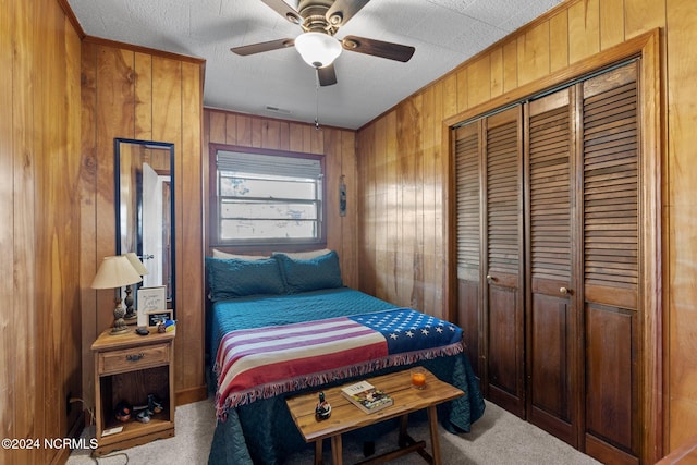 carpeted bedroom featuring a closet, wood walls, a textured ceiling, and ceiling fan