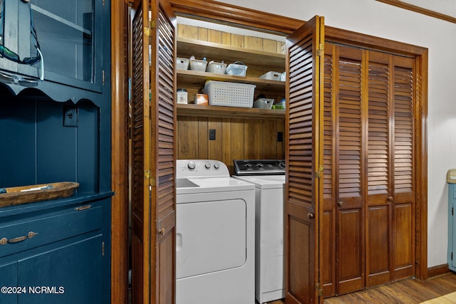 clothes washing area featuring independent washer and dryer, wood-type flooring, and crown molding