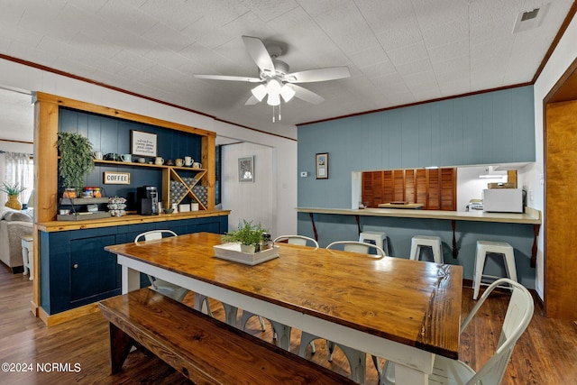 dining area with wood walls, ornamental molding, dark wood-type flooring, and ceiling fan