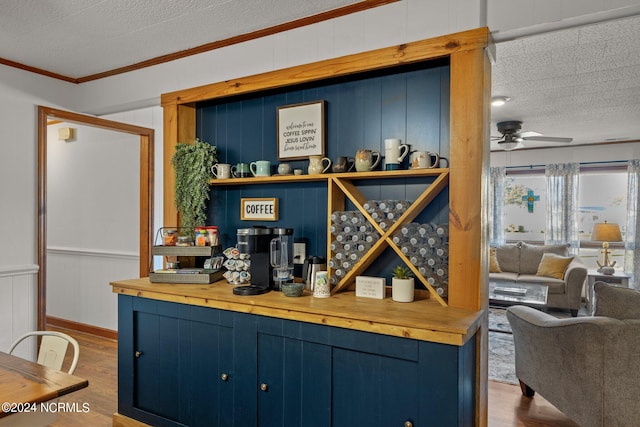 bar with crown molding, a textured ceiling, hardwood / wood-style flooring, and blue cabinets