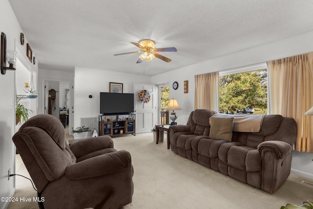 living room featuring light carpet, a textured ceiling, and ceiling fan