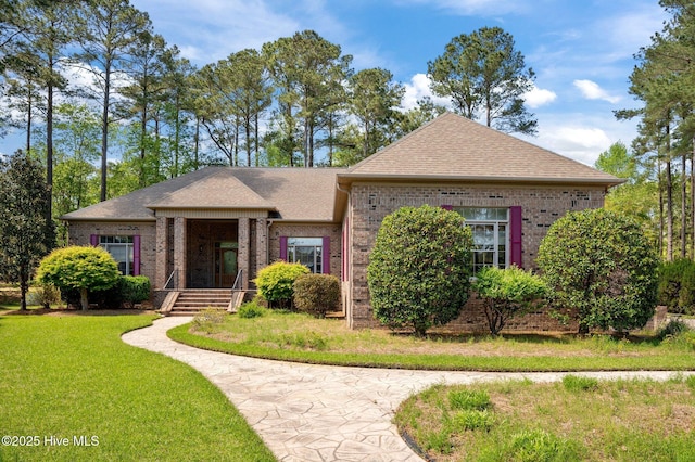 view of front of house featuring brick siding, a front yard, and roof with shingles