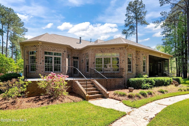 view of front of property with brick siding, a sunroom, and a front lawn