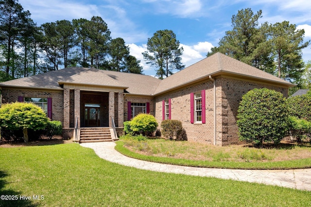 ranch-style home featuring brick siding, a shingled roof, and a front yard