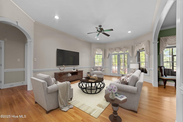 living room featuring light wood-type flooring, ornamental molding, and ceiling fan