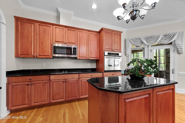 kitchen with brown cabinetry, a notable chandelier, stainless steel appliances, and light wood finished floors