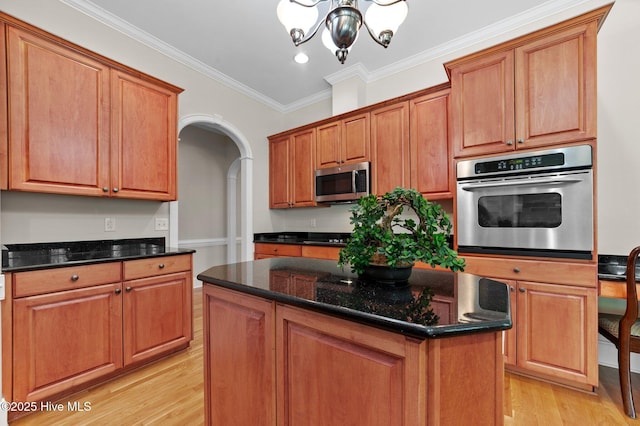kitchen with crown molding, a chandelier, light wood-type flooring, arched walkways, and appliances with stainless steel finishes