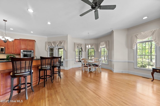 kitchen featuring dark countertops, brown cabinetry, light wood finished floors, baseboards, and appliances with stainless steel finishes