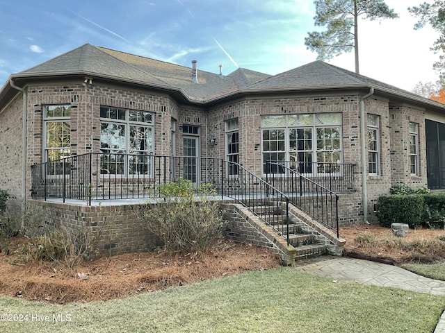 exterior space featuring brick siding and a shingled roof