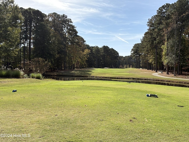 surrounding community featuring golf course view, a yard, and a water view