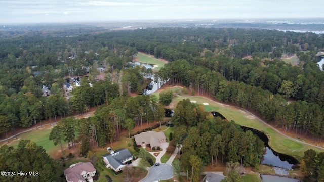 drone / aerial view with a water view, golf course view, and a wooded view