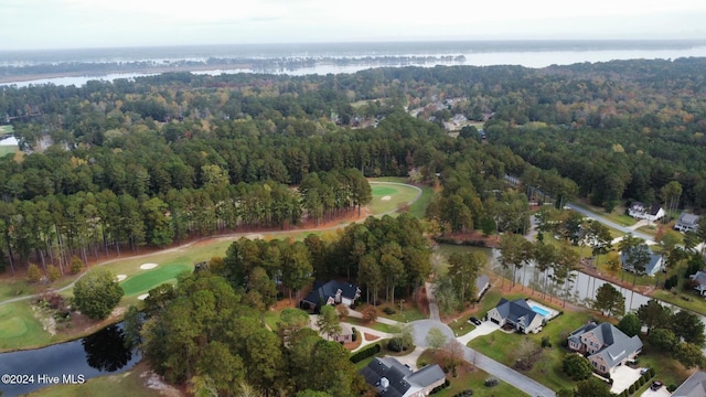 drone / aerial view with a wooded view, golf course view, and a water view