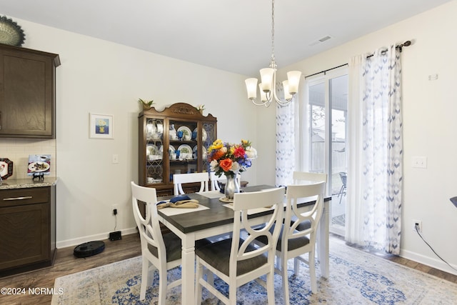 dining space featuring a chandelier, visible vents, baseboards, and wood finished floors