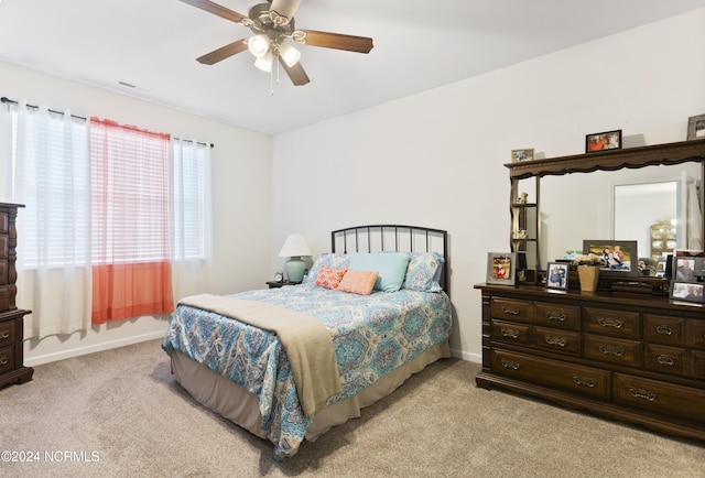 bedroom with ceiling fan, visible vents, baseboards, and light carpet