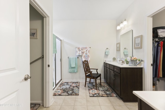 full bath with tile patterned flooring, a spacious closet, baseboards, a stall shower, and vanity