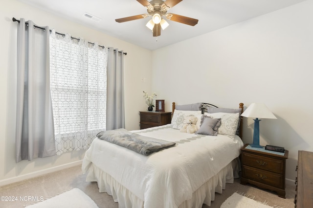 carpeted bedroom featuring a ceiling fan, visible vents, and baseboards