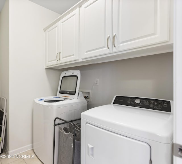 laundry area featuring light tile patterned floors, cabinet space, baseboards, and washer and clothes dryer