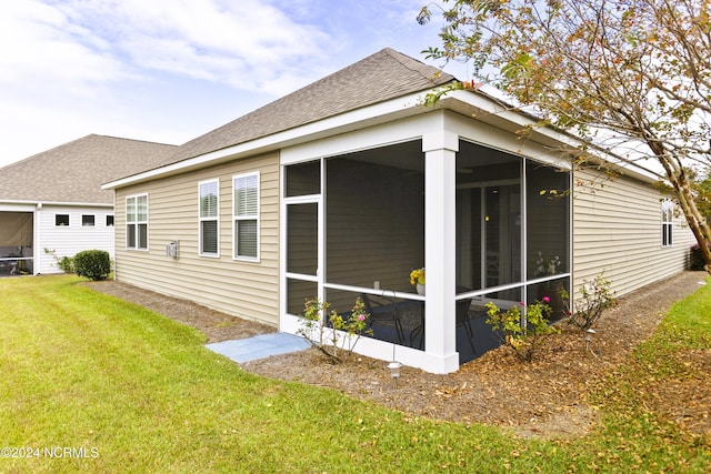 view of side of property featuring a lawn, roof with shingles, and a sunroom