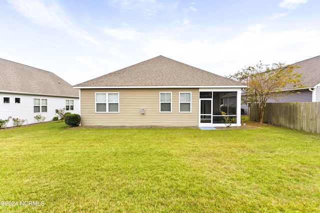 back of property with a yard, fence, a sunroom, and a shingled roof