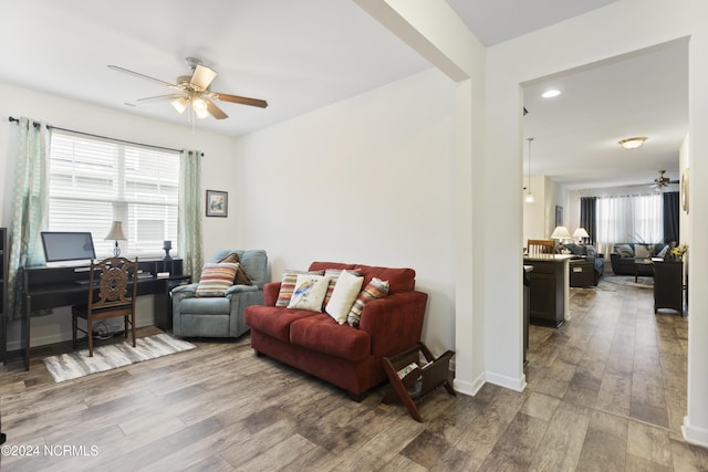 living area with wood finished floors, a ceiling fan, and baseboards