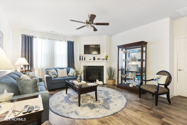 living room with ceiling fan, plenty of natural light, wood finished floors, and a large fireplace