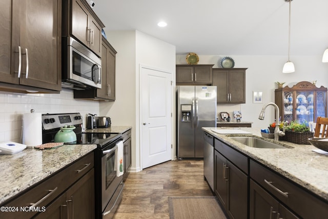 kitchen featuring light stone countertops, a sink, decorative backsplash, dark brown cabinetry, and appliances with stainless steel finishes