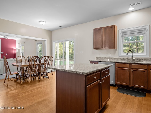 kitchen with light hardwood / wood-style flooring, stainless steel dishwasher, a kitchen island, and sink