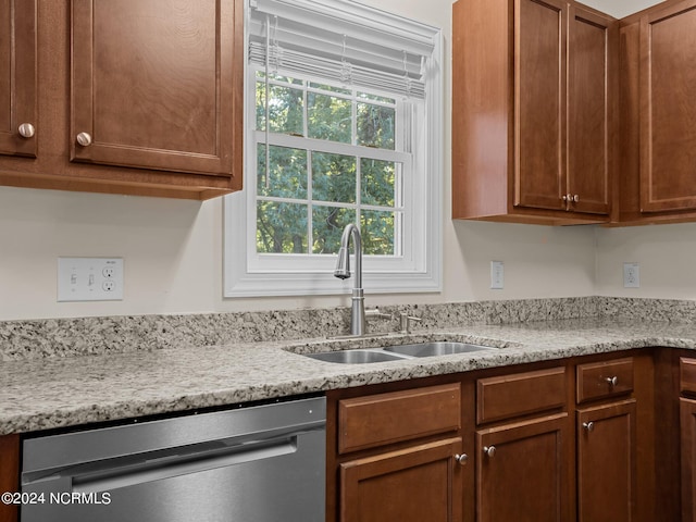 kitchen featuring dishwasher, light stone countertops, and sink