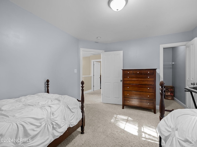 carpeted bedroom featuring a walk in closet and a closet