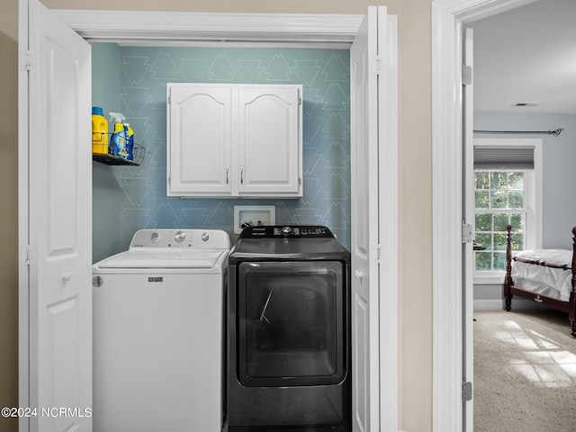 clothes washing area featuring carpet flooring, washer and clothes dryer, and cabinets