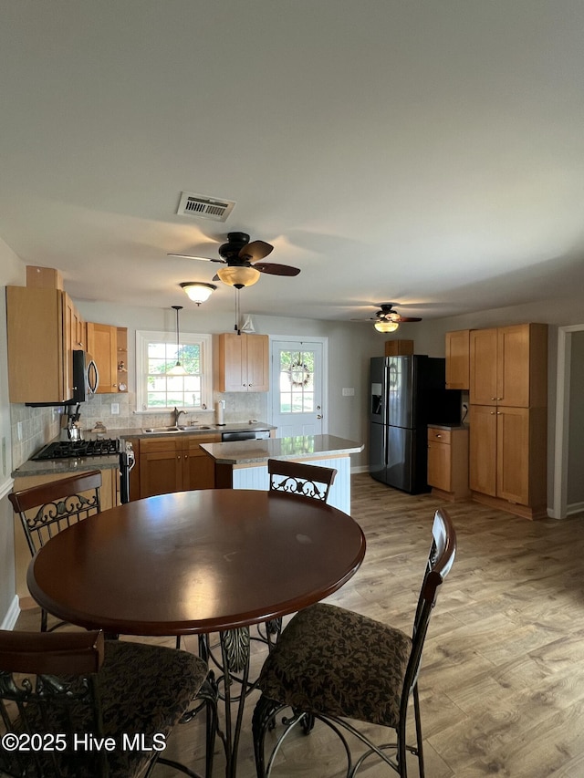 dining area with ceiling fan, sink, and light wood-type flooring