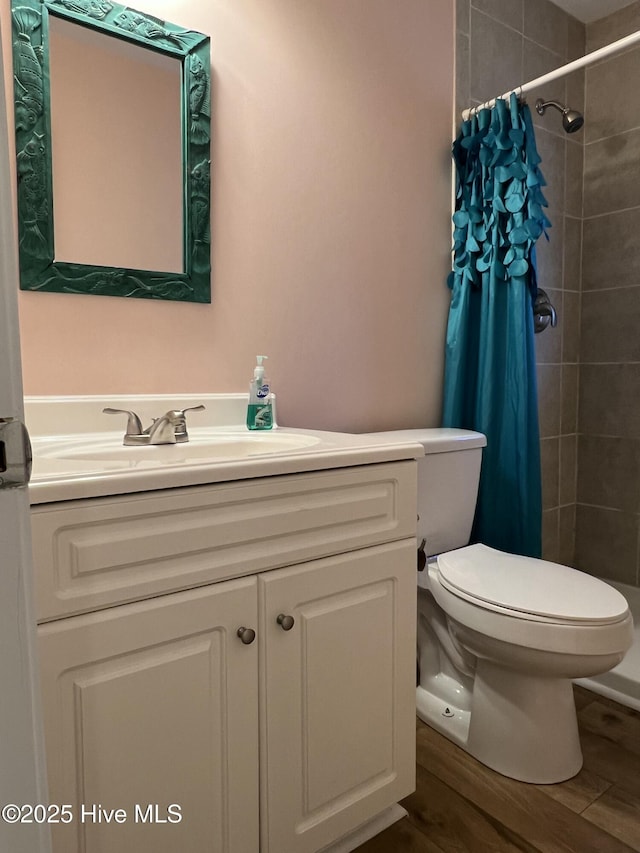 bathroom featuring a shower with shower curtain, hardwood / wood-style floors, vanity, and toilet