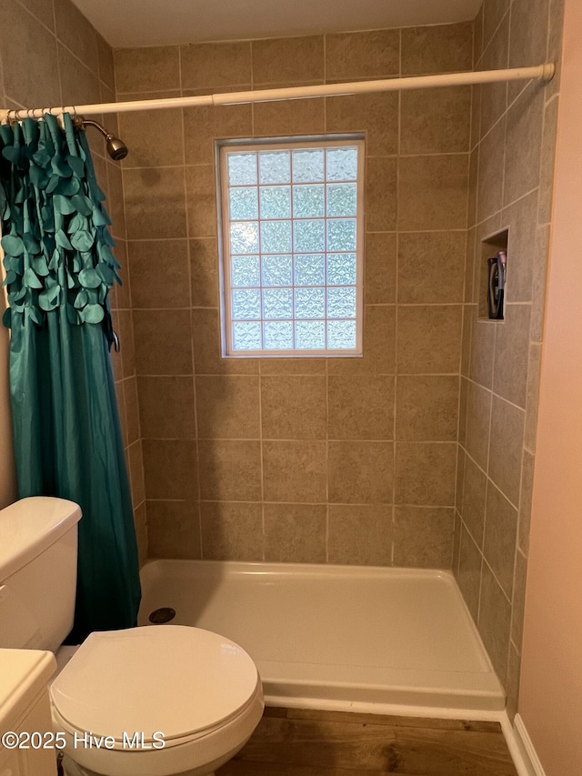 bathroom featuring a shower with shower curtain, hardwood / wood-style floors, and toilet