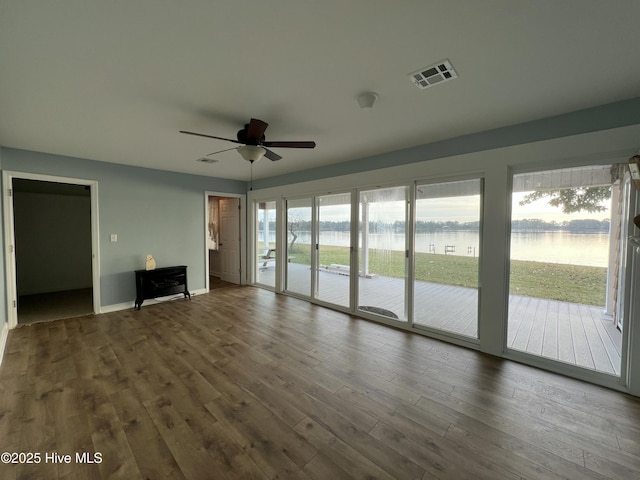 unfurnished living room featuring hardwood / wood-style floors, ceiling fan, and a water view