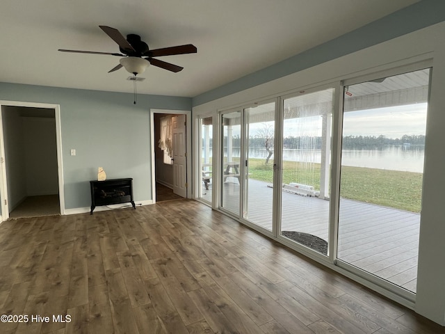 interior space with ceiling fan, a water view, and hardwood / wood-style flooring