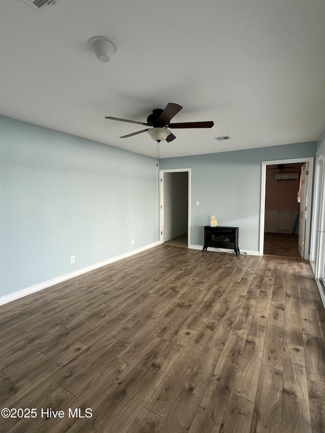 unfurnished living room featuring a wall unit AC, ceiling fan, and dark hardwood / wood-style floors