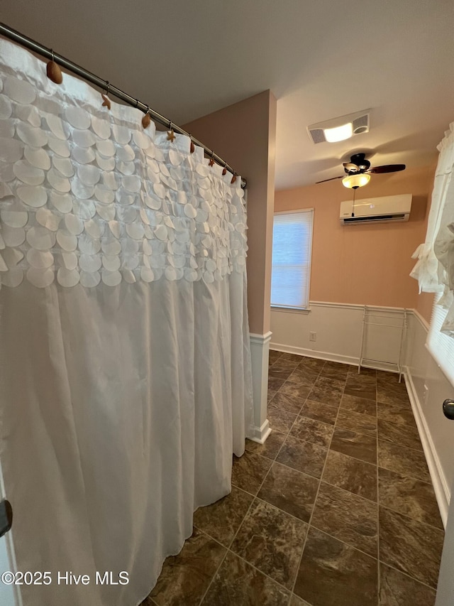 bathroom with a wall unit AC and ceiling fan