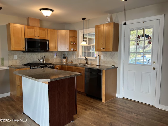 kitchen featuring a center island, sink, hanging light fixtures, backsplash, and black appliances