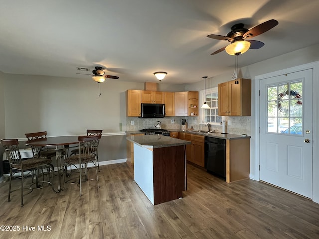 kitchen with sink, hardwood / wood-style floors, pendant lighting, a kitchen island, and black appliances