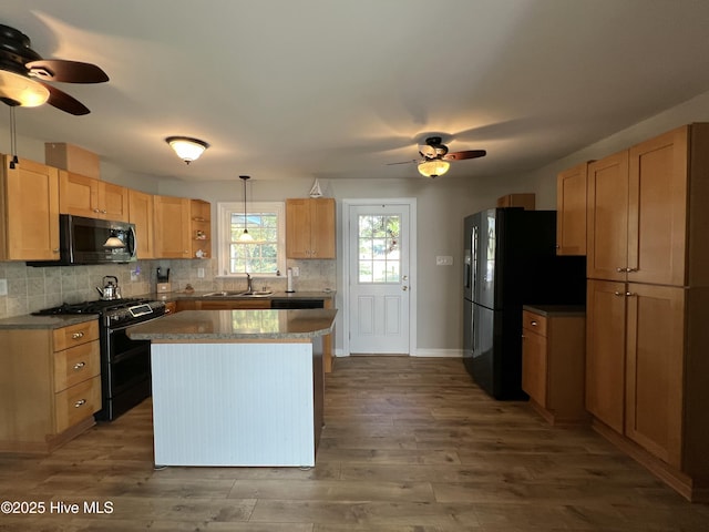 kitchen featuring sink, black appliances, wood-type flooring, a kitchen island, and hanging light fixtures