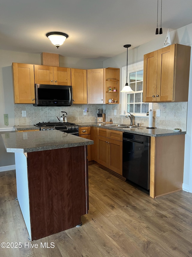 kitchen featuring tasteful backsplash, sink, black appliances, hardwood / wood-style flooring, and hanging light fixtures