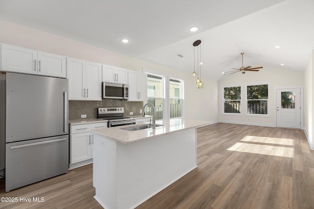 kitchen with hanging light fixtures, stainless steel appliances, an island with sink, white cabinetry, and sink